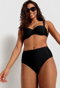 Čierny bikini set s balkónikovým vrchom s kosticou a vysokými nohavičkami. Hladká látka, minimálne švy, bez vzorov.