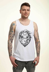 Hvid bomulds tanktop med et detaljeret sort grafisk motiv af et løvens ansigt inden for en hjerteform, omgivet af stiliserede tegn og elementer.
