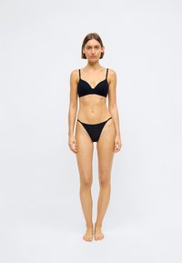 Μαύρο σετ μπικίνι που περιλαμβάνει σουτιέν χωρίς μπανέλες με ελαστικούς ιμάντες και ψηλές ριγέ εσώρουχα. Απλός σχεδιασμός και λεία υφή.