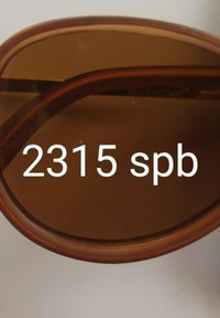 Occhiali da sole marroni con una montatura spessa e arrotondata e lenti polarizzate. La parte interna della montatura presenta un numero di modello stampato "2315 spb."