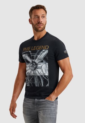 Black cotton t-shirt featuring a graphic print of a turbine, with "PME LEGEND" in gold lettering. Short sleeves and crew neckline.