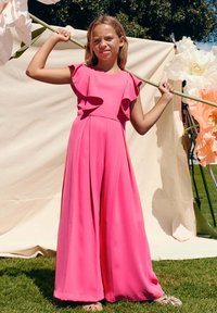 Tutina fucsia con maniche a farfalla e gambe larghe. Tessuto leggero che scende in modo elegante, completato da una silhouette fluida.