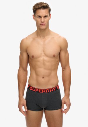 Męskie czarne bokserki z czerwonym paskiem z logo "SUPERDRY"; miękki materiał, dopasowany krój, gładka faktura i długość do połowy uda.