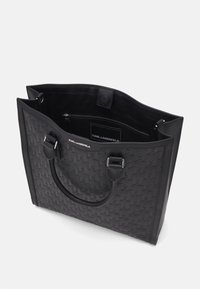 Czarna torba na ramię z teksturowanym wzorem w jodełkę, wykonana z materiału syntetycznego. Posiada podwójne uchwyty oraz kieszeń wewnętrzną na zamek.