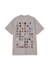 Camiseta gris de gran tamaño con un diseño de cuadrícula que presenta varios diseños e íconos impresos en múltiples colores. Manga corta y cuello redondo.