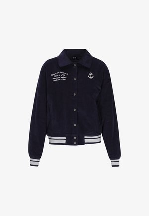 Marineblå fløjljakke med knaplukning fortil, sølvhardware, broderet tekst og hvide striber på de ribbede manchetter og kanten.