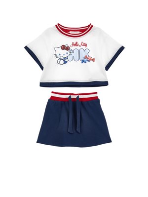 T-shirt blanc court avec bordure rouge et marine, motif Hello Kitty et bonbons, associé à une jupe marine avec une ceinture rayée rouge et blanche.