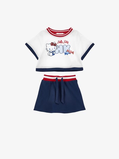 Bela kratka majica z rdečim in mornarsko modrim robom, grafiko Hello Kitty in bonboni, kombinirana z mornarsko modro krilo z rdečim in belim črtastim pasom.