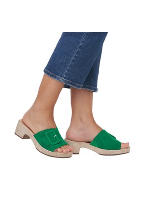 Green suede slide sandals with a wide strap featuring a rectangular buckle; textured beige block heel; open-toe design.