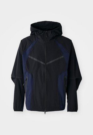 Black and navy zip-up jacket with a hood, featuring a lightweight fabric, diagonal seam accents, and side zip pockets.