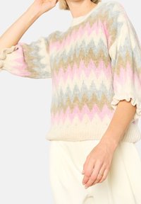 Stickad tröja med zigzag-mönster i kräm, rosa, blå och beige; har puffärmar och ribbad fåll. Mjuk textur och avslappnad passform.