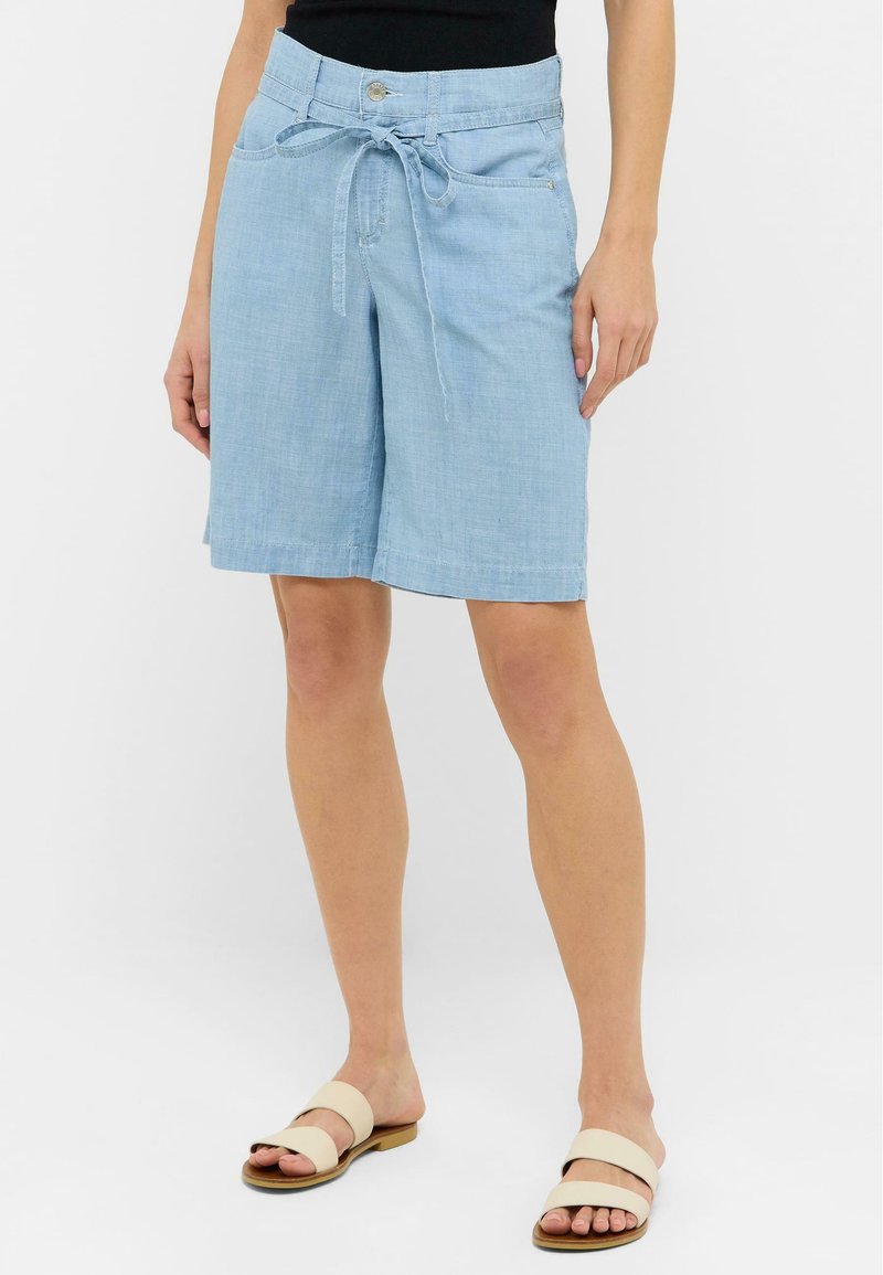 Shorts en lin bleu clair avec une taille ajustée, un détail de ceinture nouée et deux poches latérales. Texture lisse et design à la longueur du genou.