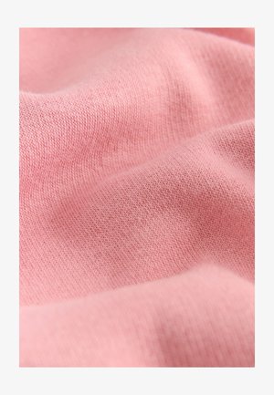 Bomuldstof i blød rosa med en glat tekstur, der har fin strik og subtile nuancevariationer, som skaber et blødt fald.