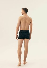 Schwarze Boxerbriefs mit dezentem Rautenmuster, elastischem Bund und weichem Stoff, von hinten auf neutralem Hintergrund betrachtet.