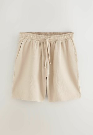 Beige texturerede shorts med elastisk talje, snørredetalje og sidelommer. Har et subtilt mønster og en afslappet pasform.