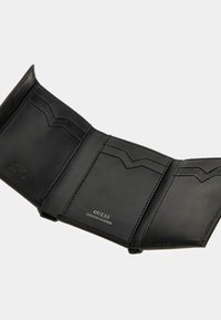 Portafoglio in vera pelle nera con tre scomparti, caratterizzato da motivi a zigzag cuciti e logo impresso "GUESS GENUINE LEATHER".