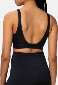 Czarny sportowy biustonosz z głębokim, okrągłym wycięciem na plecach, regulowanym zapięciem na haftkę i szerokimi ramiączkami. Materiał jest gładki, a wzór minimalistyczny.