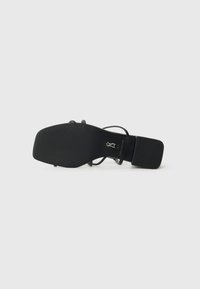 Svart sandal med teksturert såle, kvadratisk hæl og tynne stropper. Merking er synlig på innersålen. Minimalistisk design, glatt overflate.