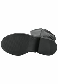Bota de cuero negra con suela de goma texturizada, con punta redondeada y sin herrajes visibles. El diseño enfatiza una forma suave y aerodinámica.