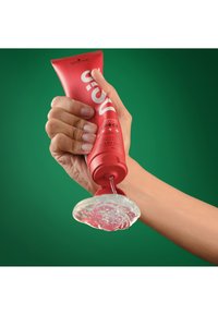 Rode tube gel wordt uitgeknepen, waarbij een heldere, stroperige gel op een hand wordt afgegeven. De achtergrond is een effen groene kleur.