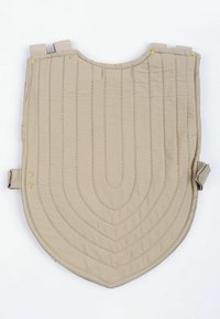 Beige gepolsterte Weste mit abgerundetem Saum, die über gesteppte Linien und goldene Druckknöpfe an den Schultern verfügt, die eine verstellbare Passform bieten.
