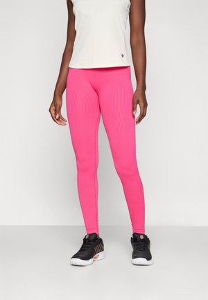 Rosa ribbet leggings, tettsittende design, kombinert med en lys farget ermeløs topp og svarte treningssko med teksturdetaljer.