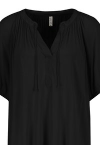 Schwarze Bluse mit V-Ausschnitt und Faltendetail an den Schultern. Weicher, leichter Stoff mit Bindebändern am Ausschnitt. Locker sitzende kurze Ärmel.