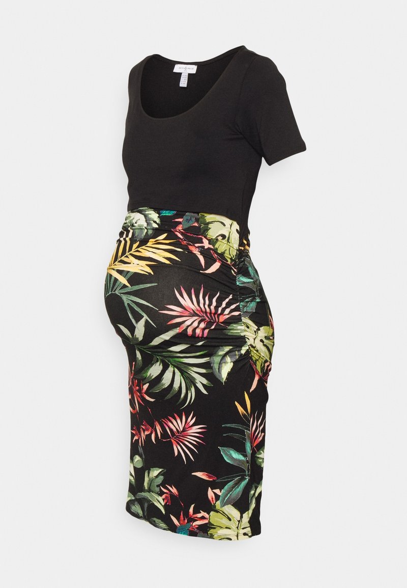 Maternity dress featuring a black top and a floral-patterned pencil skirt with tropical leaves in vibrant colors against a dark background.