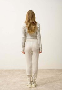 Ljust grå ribbad tröja med långa ärmar, kombinerad med matchande ljust gråa joggers med en bakficka. Texturerad tyg, avslappnad passform.