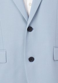Helles blaues Blazer mit einer strukturierten Stoffoberfläche, zwei schwarzen Knöpfen und zwei seitlichen Taschen mit eingekerbten Revers. Klassisches, tailliertes Design.