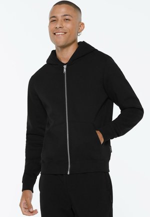 Schwarze Zip-Hoodie mit vorderer Tasche, gerippten Bündchen und Kapuze mit Kordelzug. Glatte Textur mit silbernem Reißverschlussdetail.
