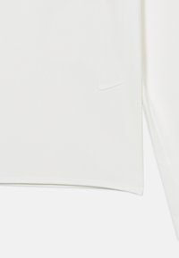 Λευκό αθλητικό μπλουζάκι από λείο ύφασμα με διακριτική υφή και μικρό λευκό λογότυπο Nike στο μπροστινό μέρος.