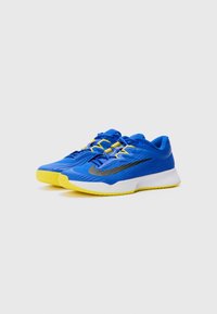 Baskets de sport bleues avec des accents jaunes. Tige en matériau synthétique avec un motif texturé. Semelle blanche légère avec un design de bande de roulement rainuré.