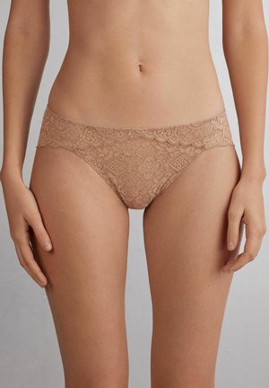 Koronkowy bikini w kolorze nude, z motywem kwiatowym, gładkim paskiem w talii i półprzezroczystą teksturą, zapewniający delikatny wygląd.