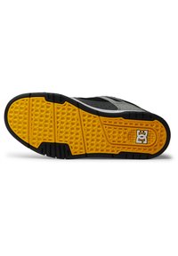 Čierna a šedá podrážka skate topánky s hexagonálnym žltým vzorom, obsahujúca čierne trakčné línie a výrazné logo na päte.