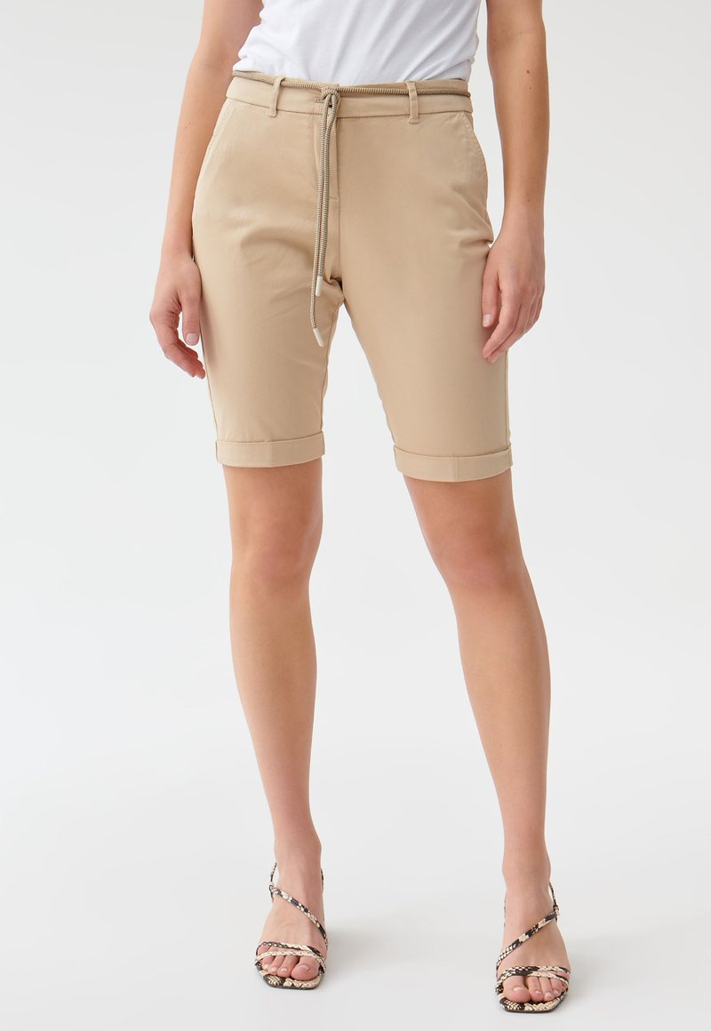 Šviesiai rudos (beige) šortai, pagaminti iš glotnios medžiagos, su raišteliu liemens juostoje, sukamuoju kraštu ir prigludusia forma.