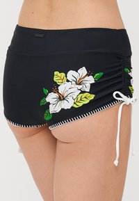 Black swim shorts with floral white hibiscus print; features white drawstrings at sides and contrasting white stitching along the hem.