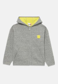 Grå zip-up hettegenser med fôret gul innside. Har en liten logo-patch på brystet og to frontlommer. Glatt tekstur.
