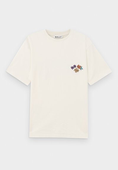 Kreemivärvi puuvillane T-särk, millel on ümmargune kaelus ja lühikesed varrukad. Vasakul rinnaosal on lilleline tikand, kus on purpur, pruun ja oranž värv.