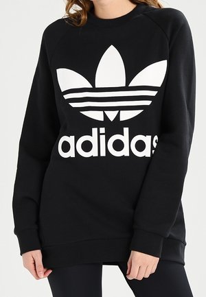 Sort sweatshirt med hvid Adidas-logo, der har et stort trefoil-grafik og fed tekst. Lavet af blødt stof med ribstrikkede manchetter og kant.