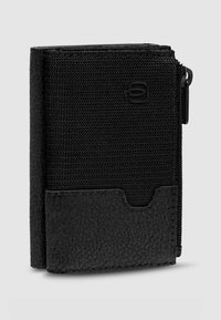 Cartera negra con parte superior de tela texturizada y parte inferior de cuero liso. Cuenta con un compartimento con cremallera y una ranura para tarjetas en la parte frontal.