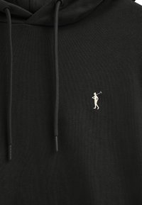 Felpa nera con cappuccio realizzata in tessuto testurizzato, con tasca a marsupio frontale. Presenta lacci neri e un piccolo logo di un golfista ricamato in bianco.