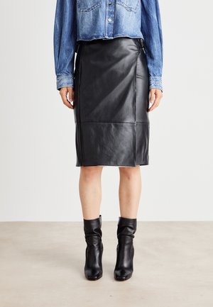 Falda lápiz de cuero negro con acabado liso, hasta la rodilla, con cintura alta y abertura lateral, combinada con una camisa de mezclilla abotonada.