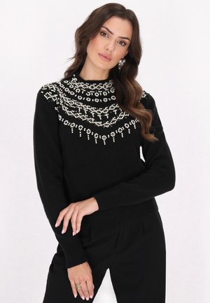 Maglione nero a maglia con collo alto, caratterizzato da intricate decorazioni in perle bianche lungo il colletto. Tessuto testurizzato e polsini aderenti.