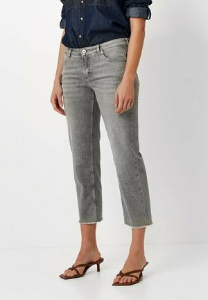 Grey cropped jeans with a straight leg design, featuring frayed hems and five-pocket styling, paired with brown strappy sandals.