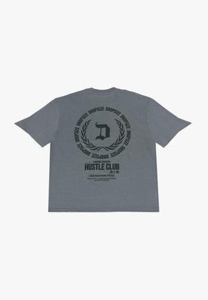 Grå bomulds t-shirt med et stort sort grafik på ryggen, der indeholder tekst og et logo i et cirkulært design. Løs pasform, korte ærmer.