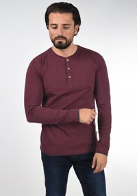 Bordeaux langemouw overhemd met een drieknoopsluiting, contrasterende donkergrijze manchetten, gemaakt van zachte stof, slim-fit ontwerp en ronde hals.