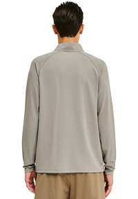 Langärmliges, kragenförmiges Hemd aus hellgrauem, strukturiertem Stoff mit einem Wabenmuster. Gerippte Bündchen und Saum, mit einem Logo nahe des unteren Rückens.