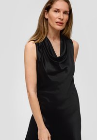 Czarna bezrękawnikowa sukienka z drapowanym dekoltem, wykonana z gładkiego materiału. Prosty krój podkreśla sylwetkę ciała z minimalnymi detalami.