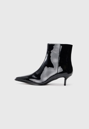 Bottine en cuir verni noir avec un bout pointu et un petit talon fin. Surface lisse sans motifs ni accessoires visibles.